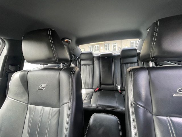 Rear and front black leather car seats with headrests; visible stitching and S logo on the front seats.