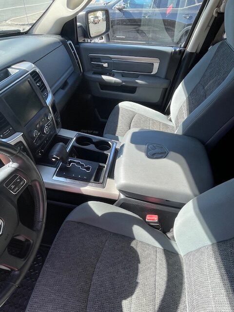 Interior of a Ram pickup truck showing front seats, center console with gear shifter and cup holders, and dashboard details.