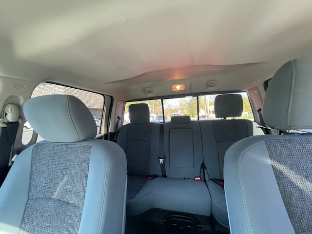 Interior of a light gray SUV showing front seats and a three-seat rear bench; dome light on.