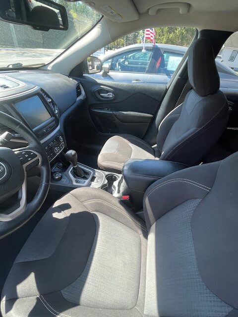 Front interior of a car: driver and passenger seats, center console, gear shifter, and dashboard visible from the passenger side window view.