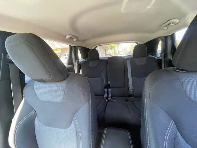 Interior of a dark cloth SUV showing three-row seating, headrests, and visible seat belts with all seats empty.