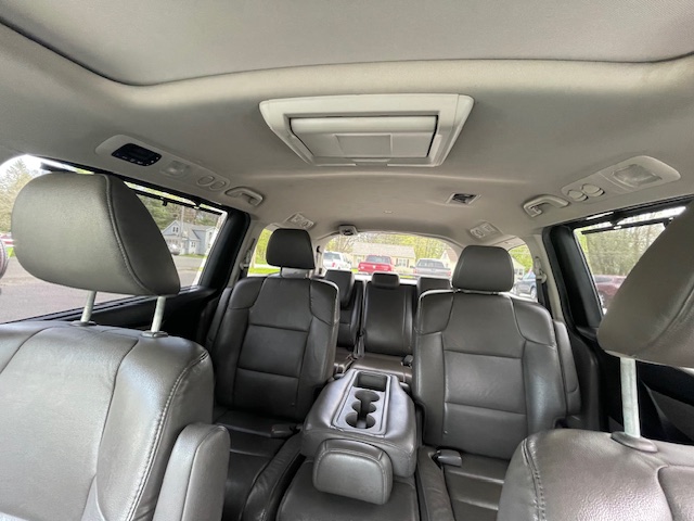 Interior of a black leather SUV with three rows of seats, center armrest with cupholders, and overhead console
