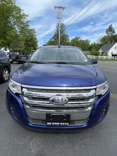 Front view of a blue Ford SUV in a parking lot, showing chrome grille and headlights.