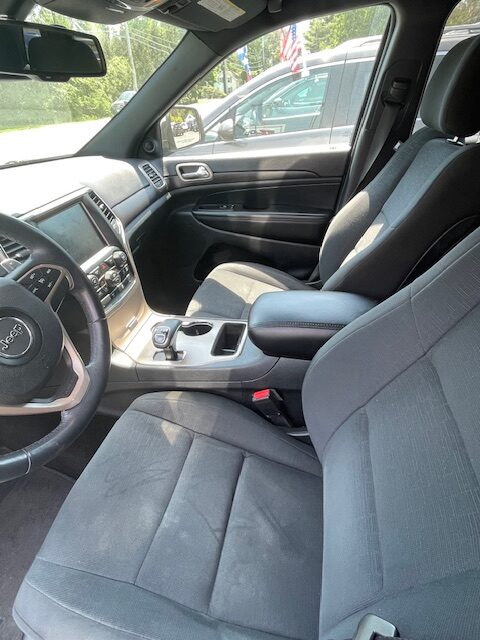 Front cabin of a gray SUV showing the steering wheel, center console, and cloth front seats from the passenger side side view.