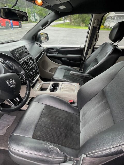 Interior view of a car's front cabin, showing the driver and passenger seats, steering wheel, and center console with cup holders.