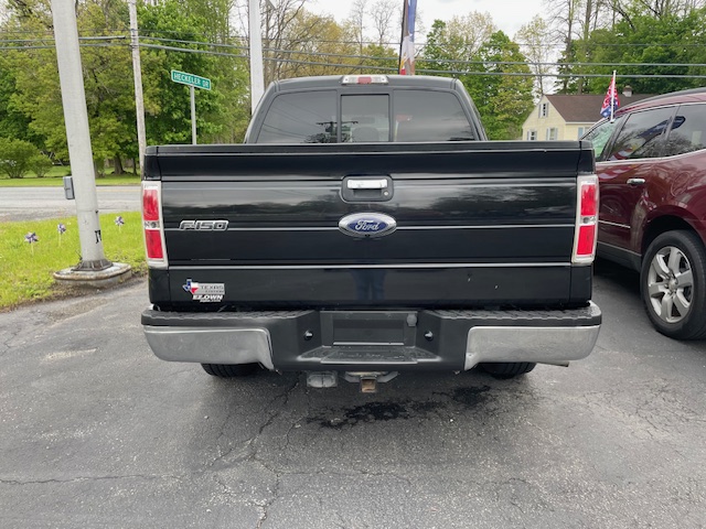 Black Ford F-150 rear view in a parking lot, tailgate closed with Ford emblem and F-150 badge visible.