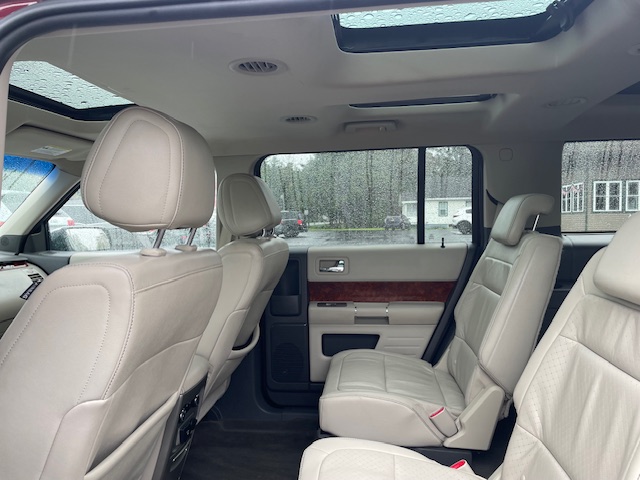 Beige leather SUV interior with two captain chairs in the middle row and a third-row seat visible, sunroof panels overhead.