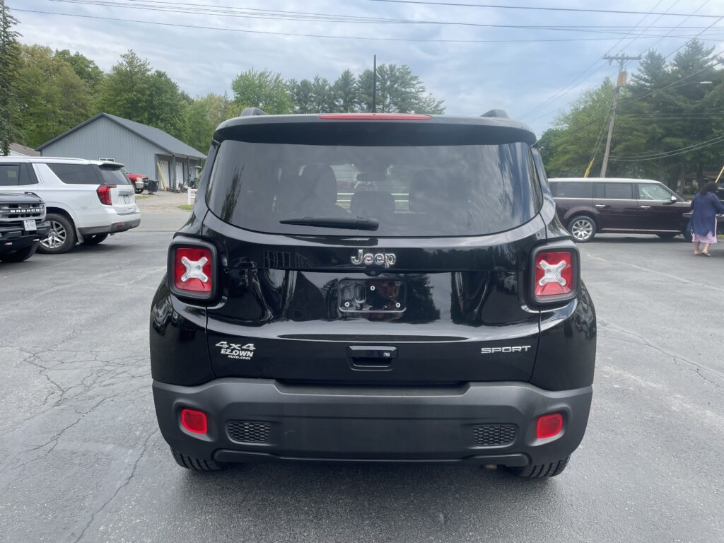 Rear view of a black Jeep SUV in a parking lot, showing 4x4 and Sport badges on the tailgate.