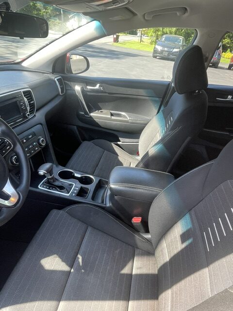 Interior of a car showing front seats, center console, and steering wheel on a sunny day outside the windows.