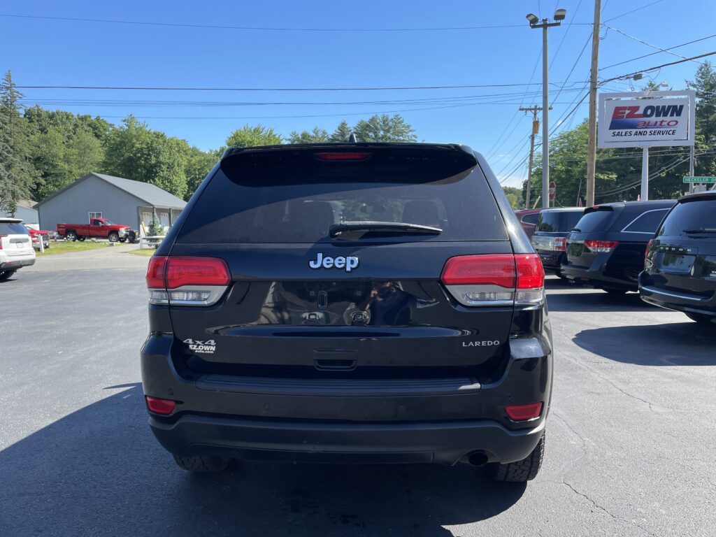 Rear view of a black Jeep SUV in a car lot with an EZOWN Auto sign in the background on the right side of the frame