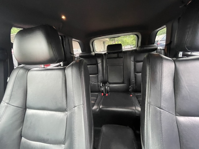 Black leather car interior with front seats and second row visible in a spacious SUV, camera at passenger level in the cabin.